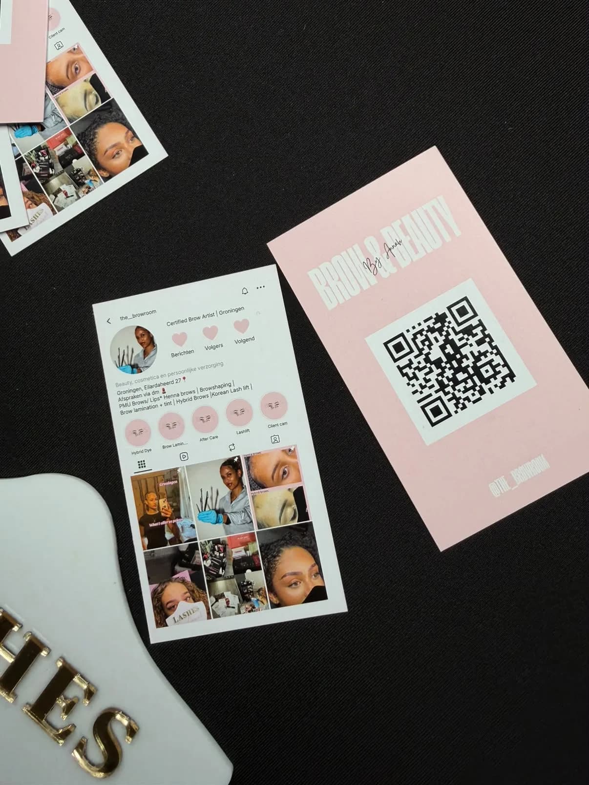 Printed The Brow Room business cards on a black table: a pink one with a QR code and one that looks like her Instagram profile